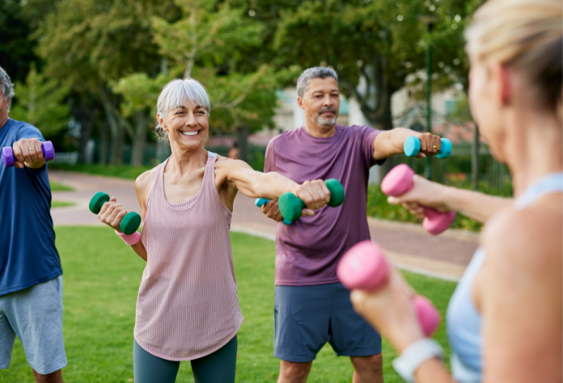 group of happy and healthy seniors exercising in the park together